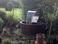 Halbrunder Cortenstahl-Brunnen mit Edelstahl-Wasserschwallbrause